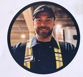 Dustin, owner of Dusty's Diesel and Auto Services, in a cap and high visibility vest